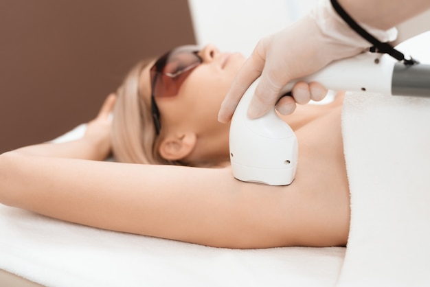 The doctor treats her armpits with an apparatus Premium Photo