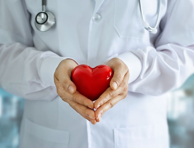 Premium Photo | Doctor with stethoscope and red heart shape in hands on ...