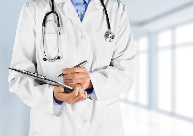 Premium Photo | Doctor with stethoscope writing on background