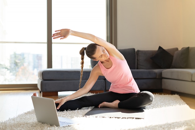 Premium Photo | Doing yoga exercises in front of the laptop