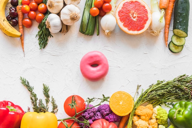 カラフルな健康と不健全な食べ物の間の白いテクスチャの背景にドーナツ 無料の写真