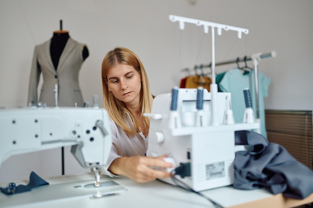 Premium Photo | Dressmaker works on sewing machine at workplace