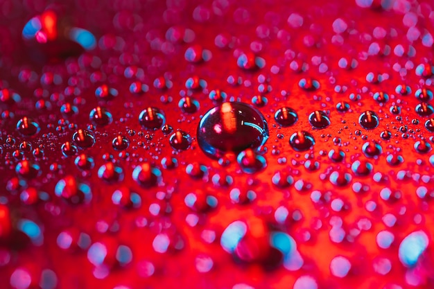 Drop of water bubbles on the surface of red background | Free Photo
