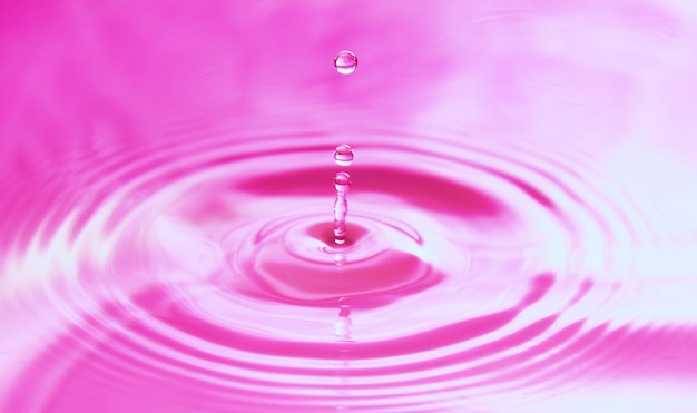 水滴が水に落ち 完全な同心円を形成します 抽象的なピンクの背景 プレミアム写真