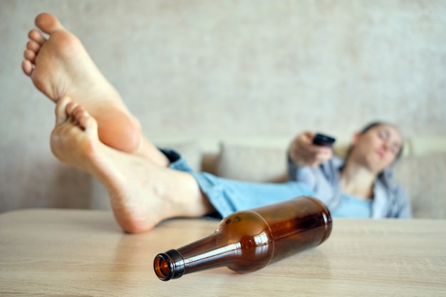 Premium Photo The Drunk Girl Lies On A Sofa Switching Channels On The Tv Legs On The Table