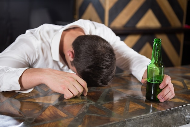 Premium Photo Drunk Man Lying On A Counter With Bottle Of Beer