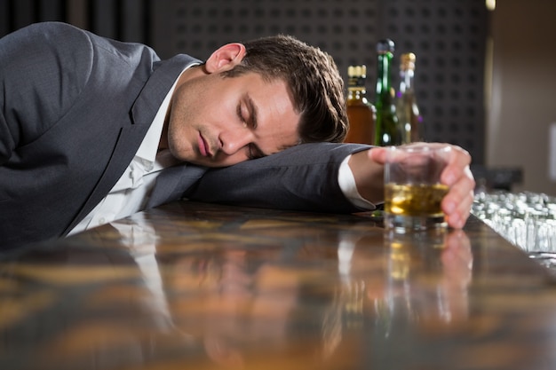 premium-photo-drunk-man-lying-on-a-counter-with-glass-of-whisky