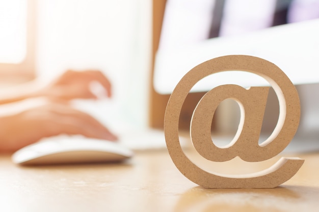 E-mail marketing concept, hand using computer sending message with wooden email address symbol Premium Photo