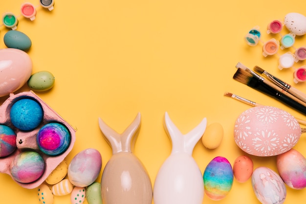 Easter eggs with bunny ears and paint brushes with space for writing the text Free Photo