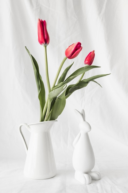 花瓶の花の束の近くのイースターのウサギ 無料の写真