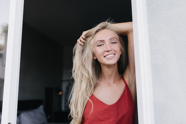 恍惚とした白人女性モデルが早朝に真摯な笑顔でポーズをとる 楽しんでいる赤いパジャマのロマンチックな格好良い女性 無料の写真