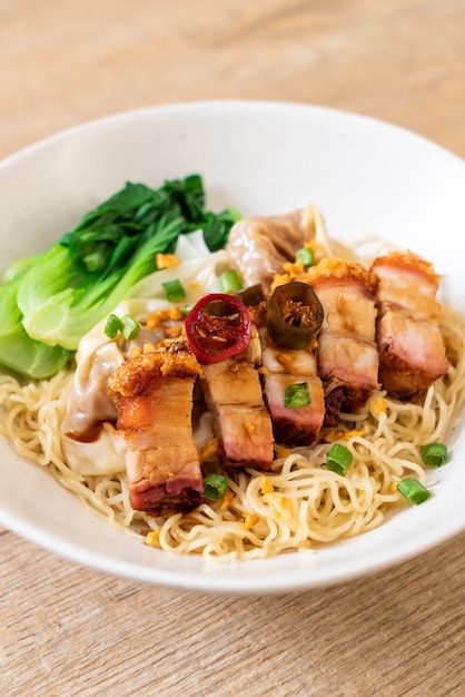 Premium Photo | Egg noodle soup with crispy pork belly and wonton