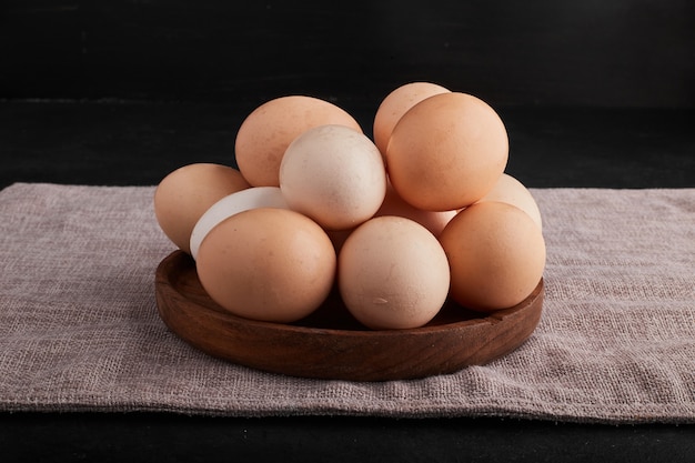 Eggs in a wooden platter on kitchen towel. Free Photo