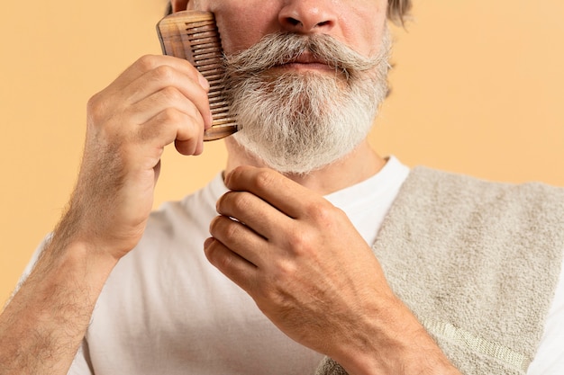 ひげをとかすタオルを持つ老人 無料の写真