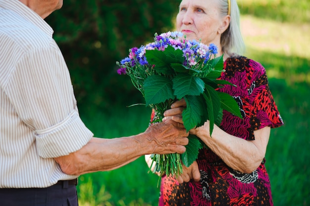 Premium Photo An Elderly Man Of 80 Years Old Gives Flowers To His Wife