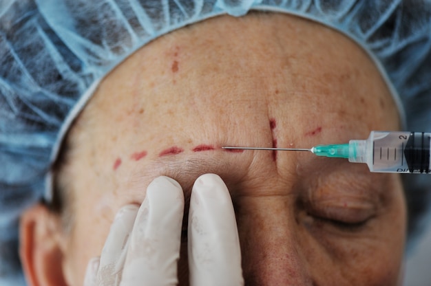Elderly woman getting botox injection procedure Premium Photo
