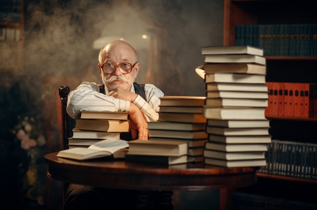 Premium Photo | Elderly writer sitting at the table with stack of books ...