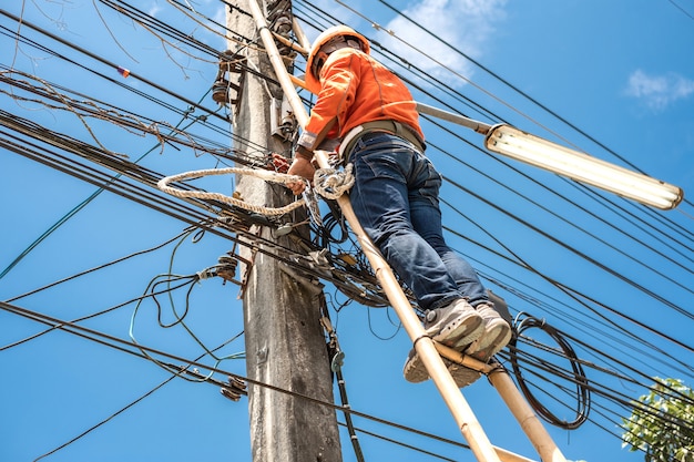 Premium Photo | Electrical lineman worker climb a bamboo ladder to ...