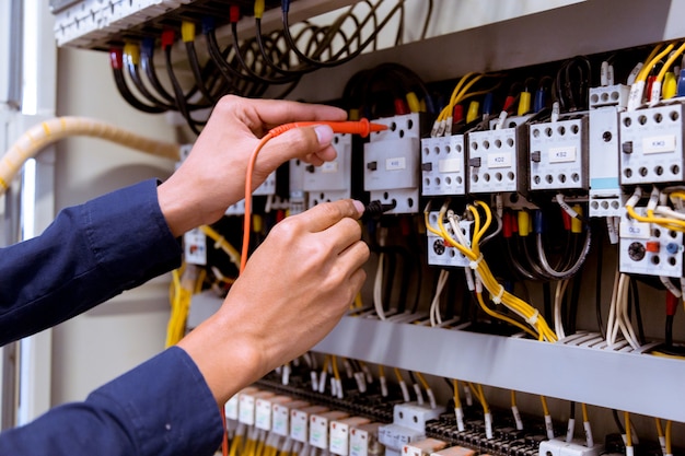 Premium Photo | Electrician testing electric current in control panel.