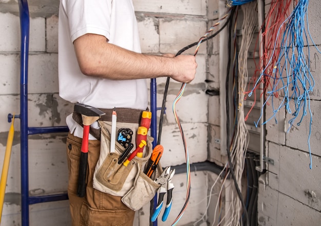 Electrician working near the board with wires. installation and connection of electrics. Free Photo