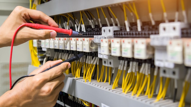 Electricians hands testing current electric in control panel. Premium Photo