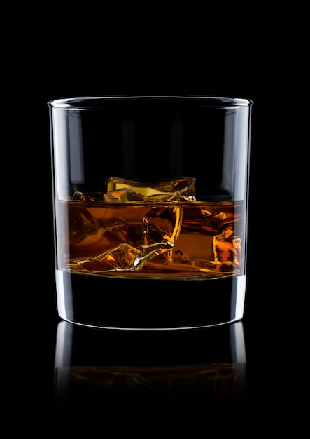 Premium Photo | Elegant glass of whiskey with ice cubes on black ...