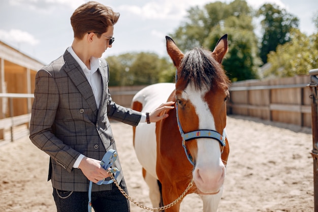 Elegant man standing next to horse in a ranch Photo | Free Download