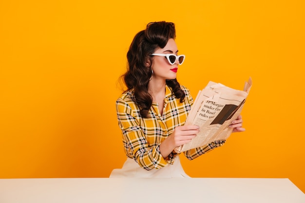 Free Photo Elegant Young Woman Reading Newspaper Studio Shot Of Concentrated Pinup Girl Posing On Yellow Background