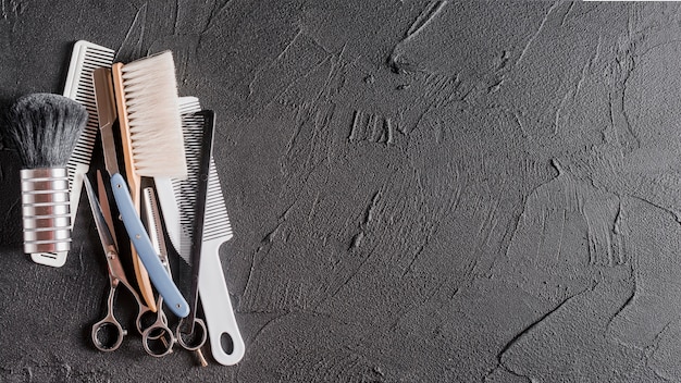 Elevated view of combs, scissors and razor on black surface Free Photo