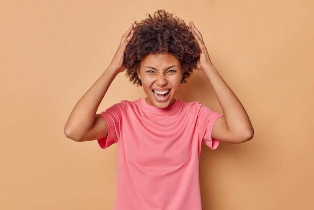 Premium Photo Emotional Curly Haired Woman Grabs Head Exclaims Loudly