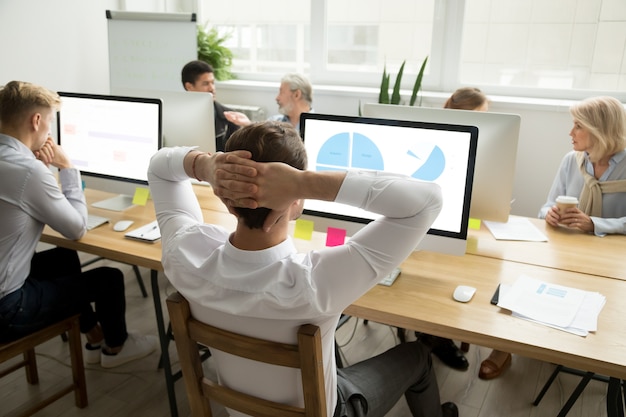 Employee analyzing statistics report sharing office desk with diverse colleagues Free Photo