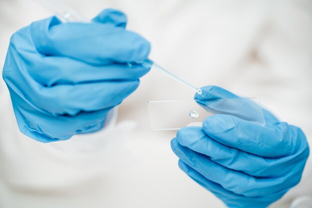 Premium Photo | Employee in blue gloves dripping light liquid onto ...