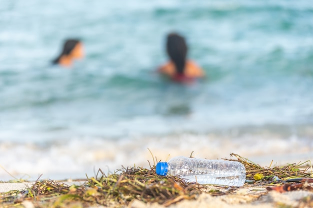 海の人々と汚い砂浜の海藻 ゴミ 廃棄物でいっぱいの空のプラスチック水bottledirtyビーチ プレミアム写真