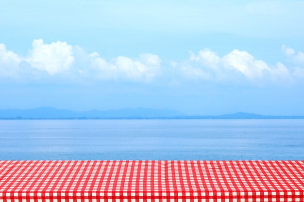 Empty Table With Red And White Tablecloth Over Blurred Sea Outdoor