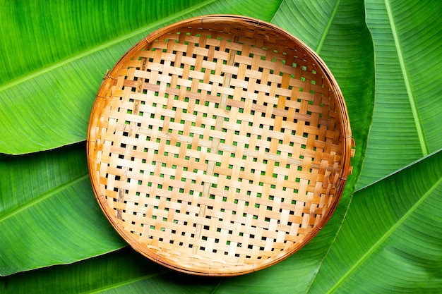 Premium Photo Empty Wooden Bamboo Threshing Basket On Banana Leaves Background Top View