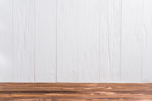 An Empty Wooden Desk Against White Painted Wall Free Photo