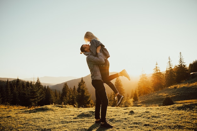 Premium Photo | Enamored guy holding a girl in his arms, a frame at sunset.