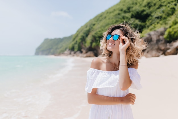 空を見ている夏服の熱狂的なヨーロッパの女性 ビーチでの休息中にポーズをとって笑顔のきれいな女性の屋外の肖像画 無料の写真