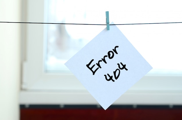 Error 404. note is written on a white sticker that hangs with a clothespin on a rope Premium Photo