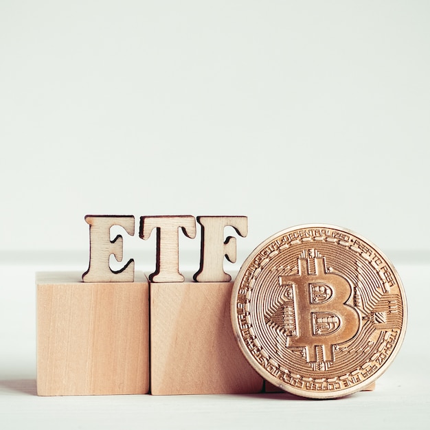 Etf letters made of wood next to a bitcoin coin. Premium Photo