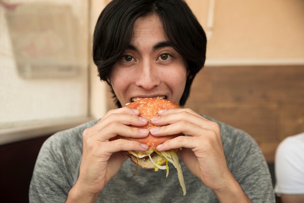 民族の男性がハンバーガーを食べるとカメラ目線 無料の写真