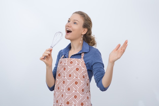 Excited housewife using whisk as microphone Free Photo