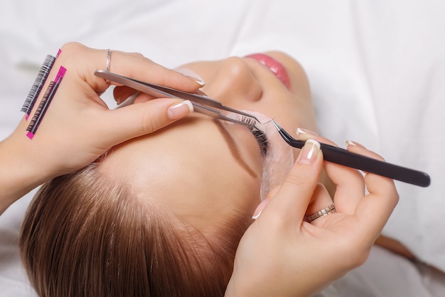 Eyelash extension procedure. woman eye with long eyelashes. Premium Photo