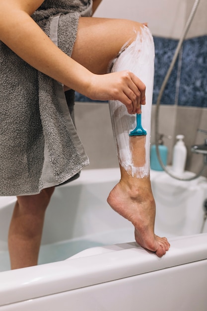 Faceless woman shaving legs | Free Photo