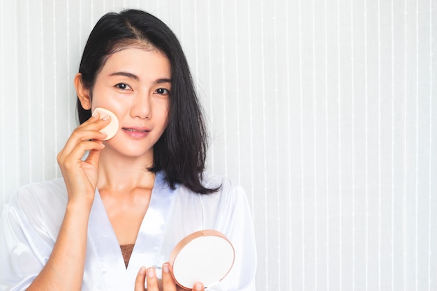 Facial makeup. beautiful asian woman applying powder on face ...