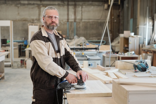 Premium Photo | Factory worker in uniform standing by workbench with ...