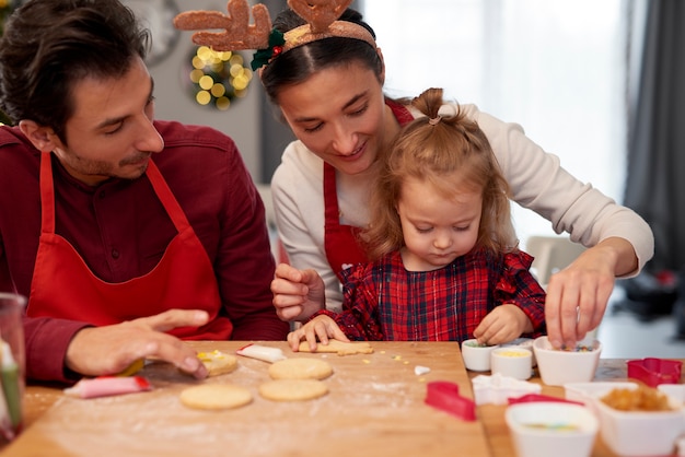 Family decorating christmas cookies together in the kitchen Free Photo