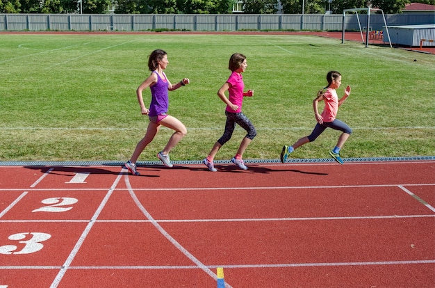 Premium Photo | Family fitness, mother and kids running on stadium ...