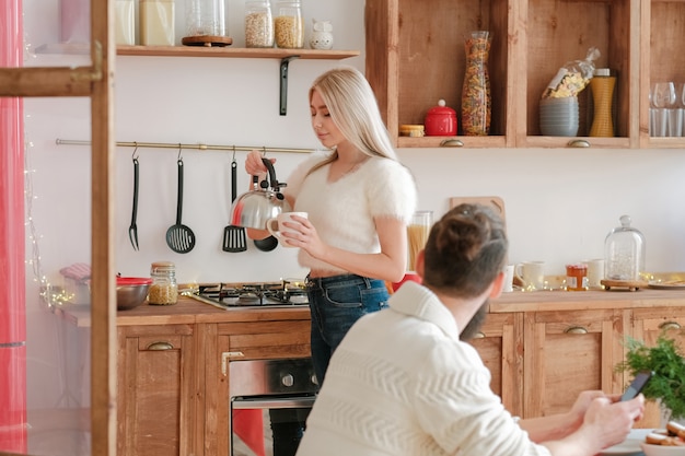 Premium Photo | Family morning. beautiful blonde lady making tea for ...