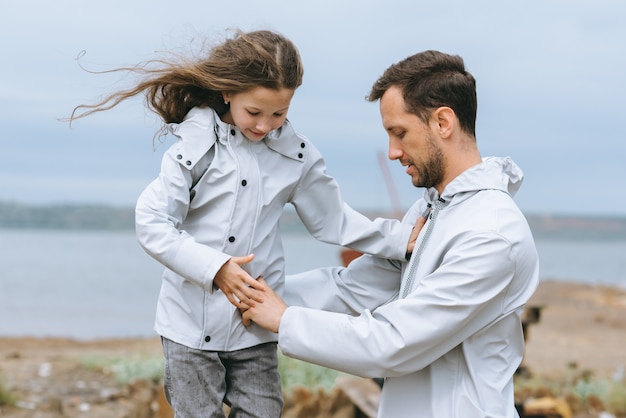 Premium Photo Family portrait of dad and dauther in raincoat near the sea image